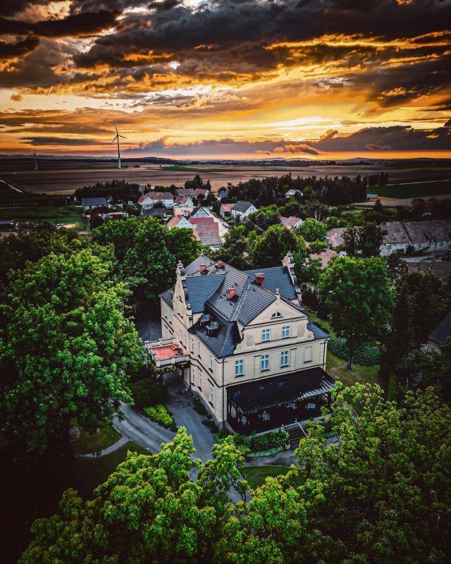 Widok z drona na budynek Pałacu Gruszów i malowniczy zachód słońca widoczny nad horyzontem