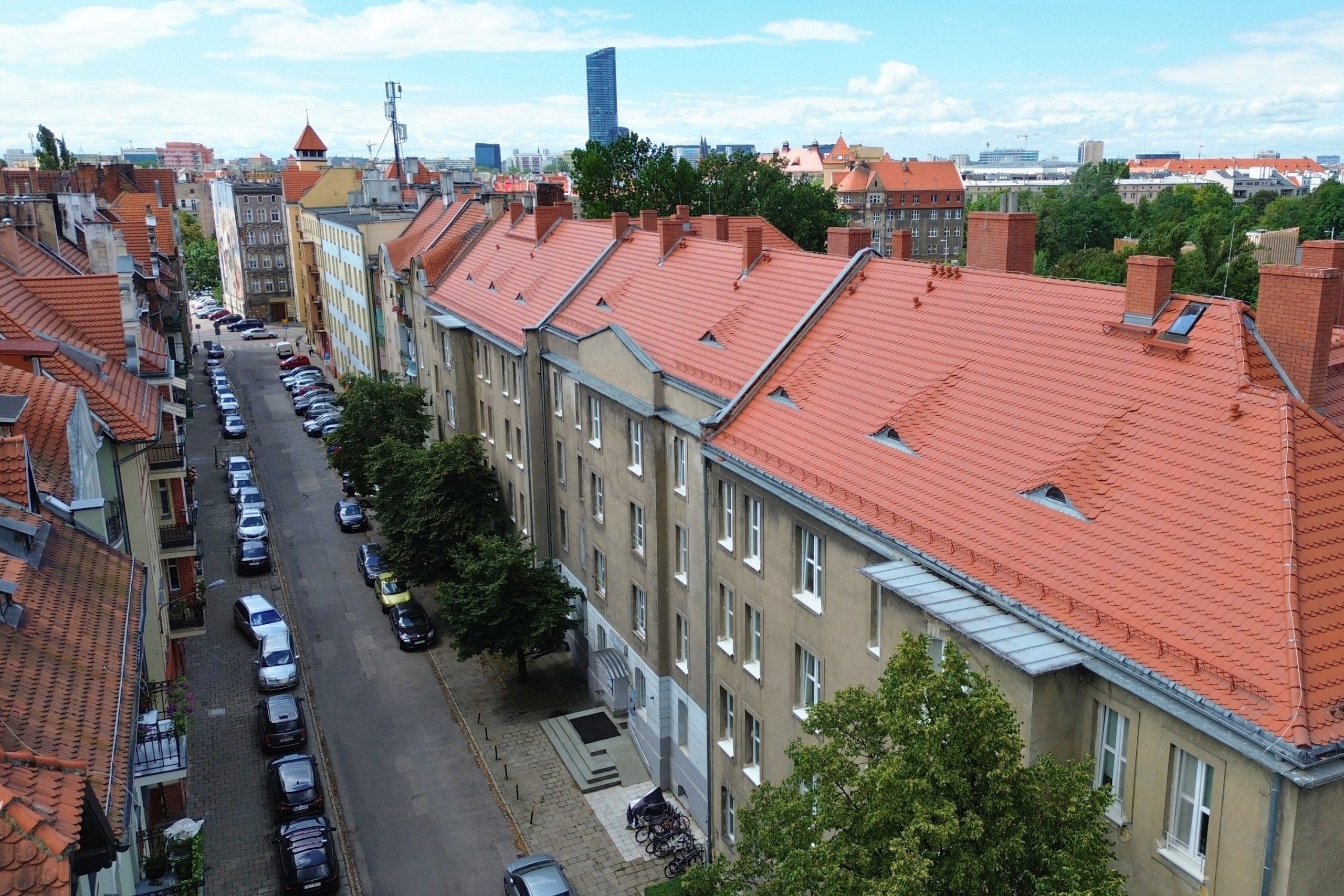 widok z drona na ulicę ze kamienicami z odnowionymi dachami. 