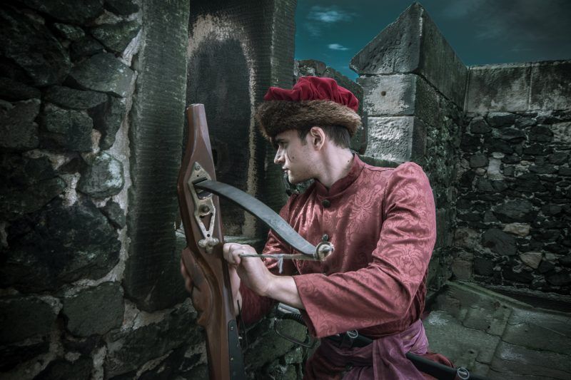 Mężczyzna w czerwonym stroju historycznym - rekonstruktor podczas warty na murach zamku Grodziec