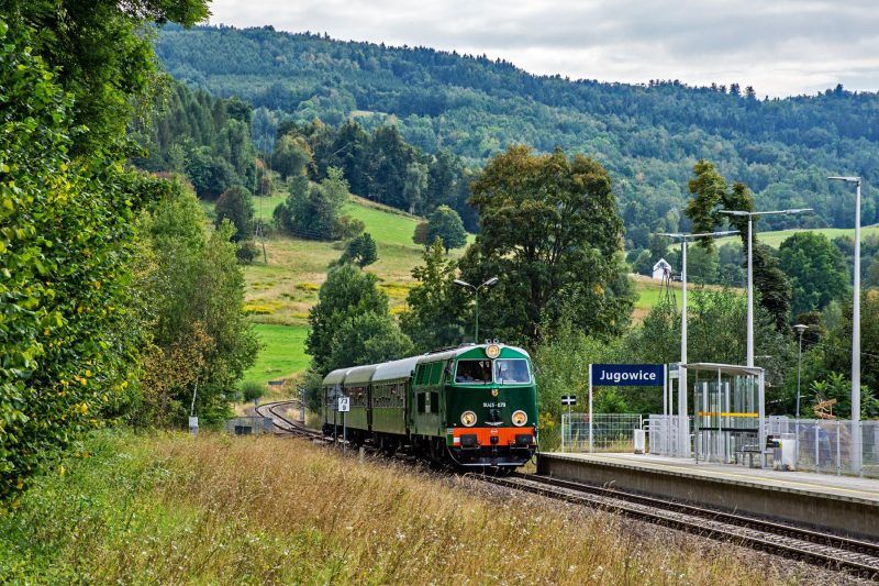 Pociąg jadący przez stację kolejową Jugowice na tle gór