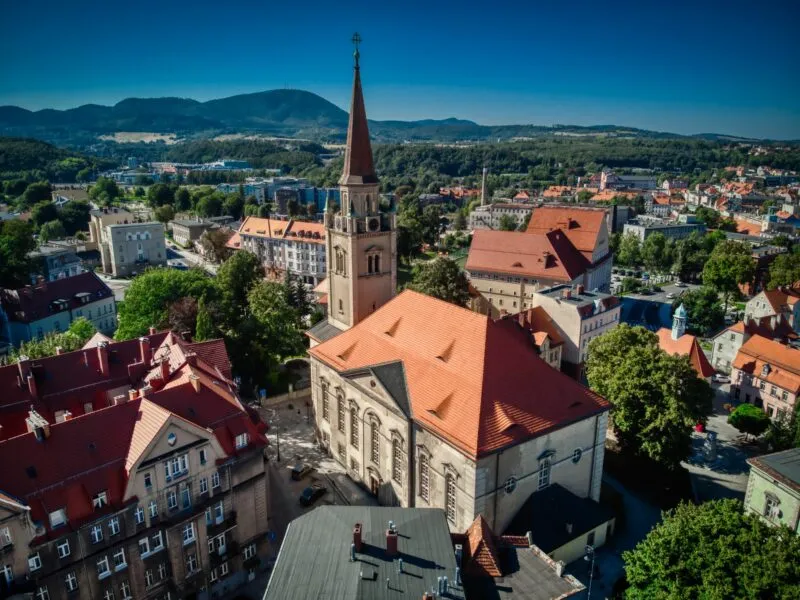 Zdjęcie z lotu ptaka na miasto z kościołem widocznym w centrum kadru i górami w tle
