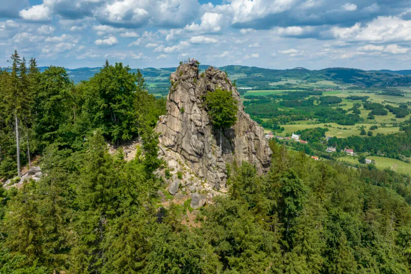Les rochers de Sokoliki s'élèvent au-dessus de la forêt verte dans les monts Rudawy Janowickie, offrant une vue étendue sur une mosaïque de champs, de villages et de chaînes de collines.