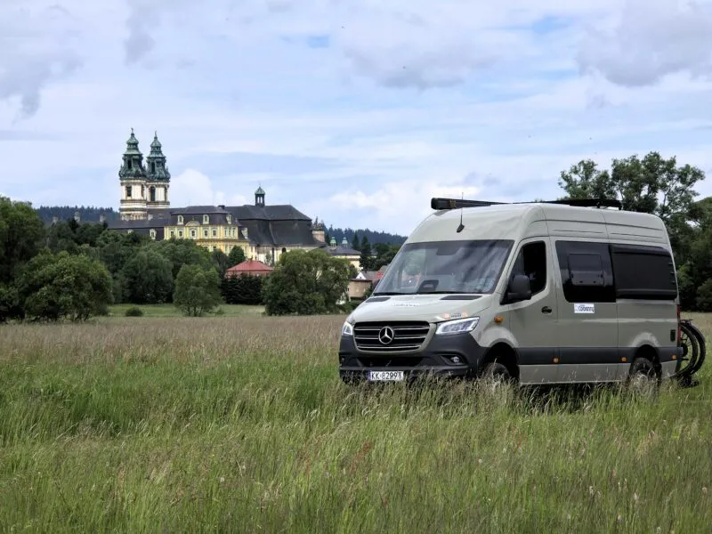 Panorama na opactwo w Krzeszowie z camperem zaparkowanym w trawie