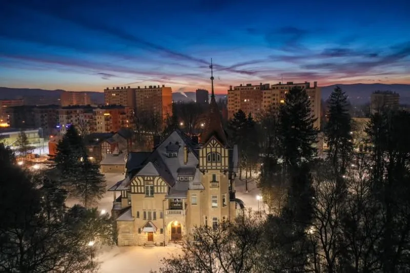 Zdjęcie nocne które przedstawia zabytkowy budynek przypominający zamek w centrum miasta