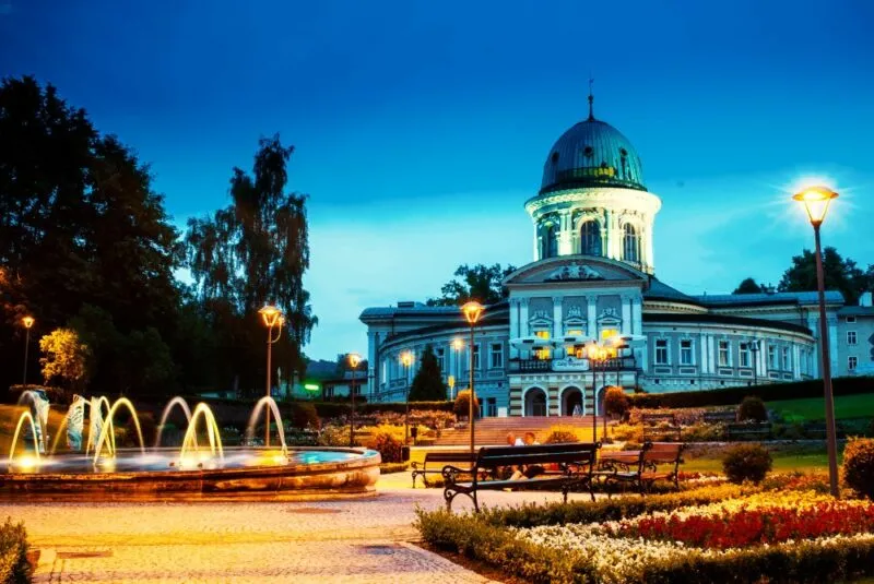 Wieczorny widok na zabytkowy budynek uzdrowiska z fontanną na pierwszym planie