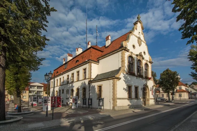 Historyczny budynek, z odnowioną elewacją w kolorze białym, poprzecinanym gzymsami z piaskowca.