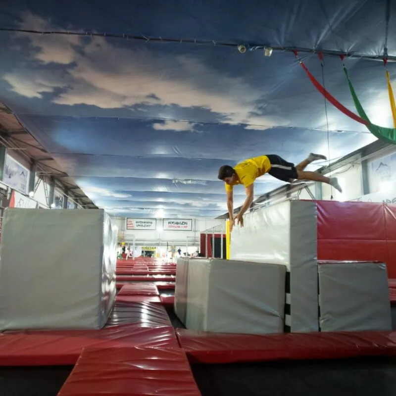 Młody człowiek, wykonujący akrobacje w parku trampolin.