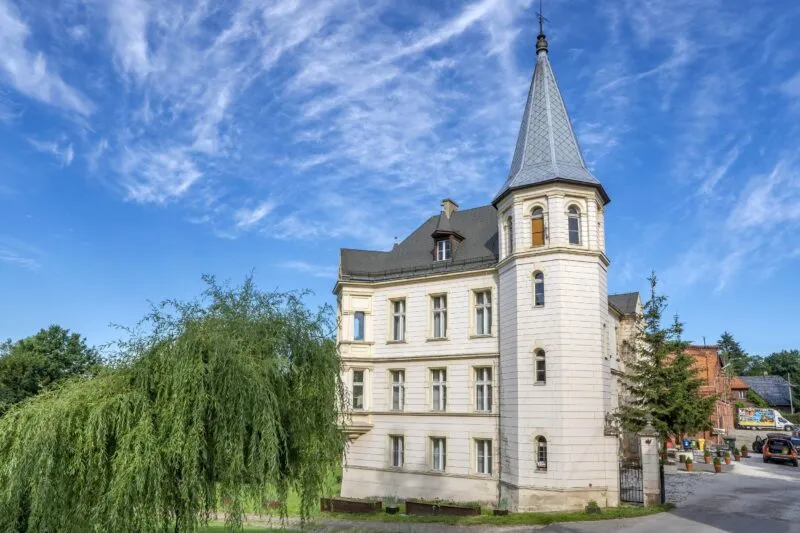 Widok na pałac, z jasną elewacją, w tle błękitne niebo.