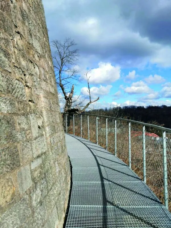 Widok na kładkę trasy okalającej zewnętrzny mur Twierdzy Kłodzko z widokiem na zabudowania Kłodzka