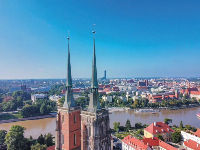 Słoneczny widok z lotu ptaka na centrum Wrocławia z dobrze widocznymi hełmami wież wrocławskiej katedry, na których widoczny jest zabezpieczony siatką taras widokowy.