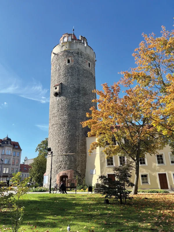Widok na skąpaną w promieniach słońca kamienną, średniowieczną, okrągłą w swym planie wieżę centrum miasta Lubań