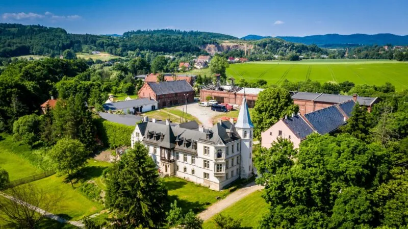Palác z ptačí perspektivy, uprostřed zeleně.