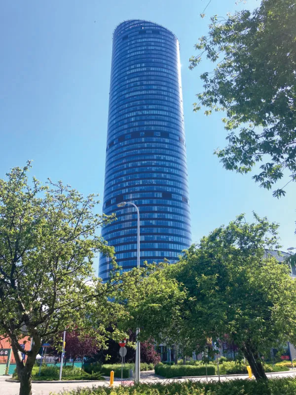 Widok z poziomu ulicy na przeszklony wieżowiec Sky Tower przy słonecznej, letniej pogodzie