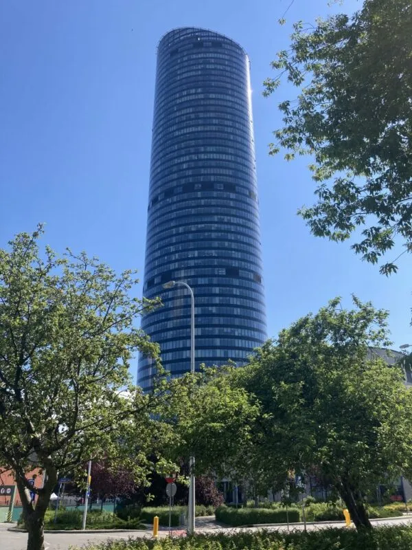 Widok z poziomu ulicy na przeszklony wieżowiec Sky Tower przy słonecznej, letniej pogodzie