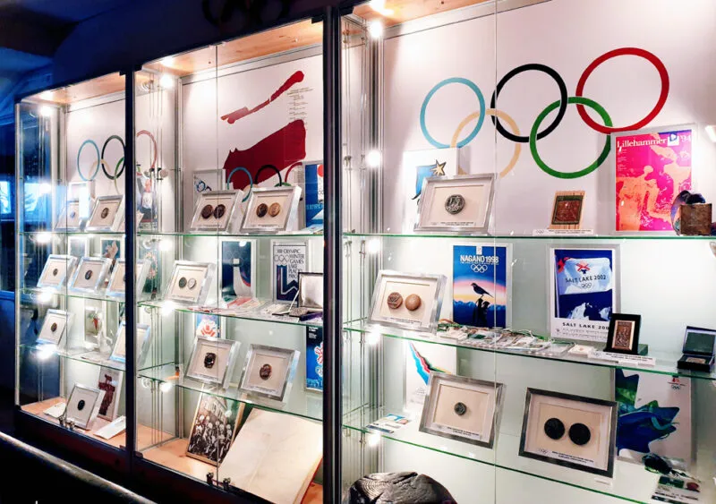 Wystawa w szklanej gablocie medali olimpijskich z flagą olimpijską