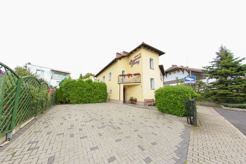 Widok na parking oraz dwukondygnacyjny budynek, z balkonem 