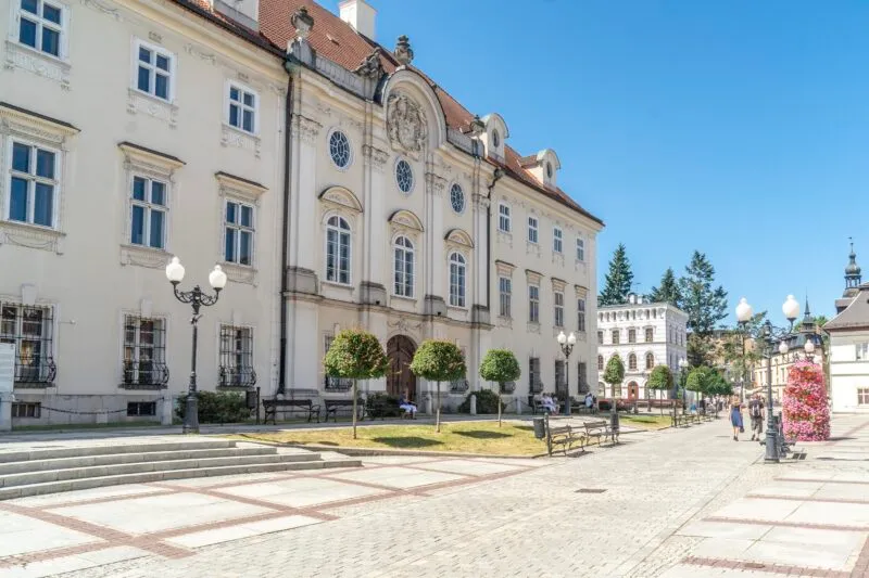 Pałac z jasną elewacją oraz czerwonym dachem, w tle błękitne niebo.