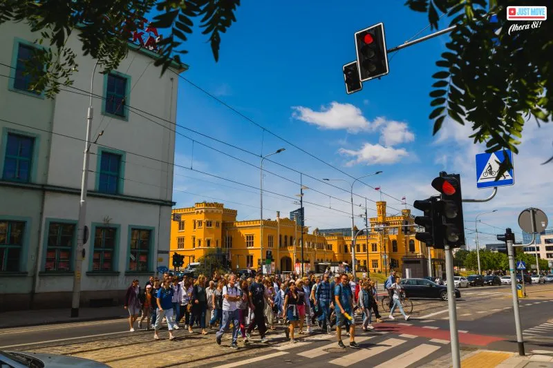 Grupa turystów - wycieczka przechodzi przez przejście dla pieszych we Wrocławiu na tle dworca wrocław główny