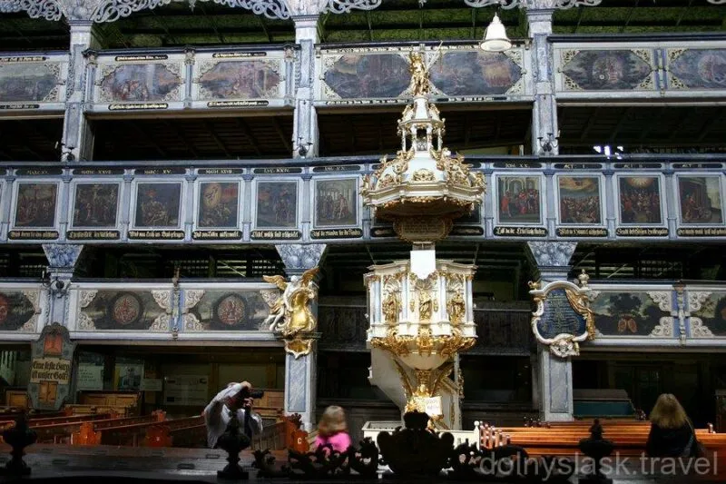 Wnętrze drewnianego kościoła z 3 piętrami oraz złoto dekorowaną amboną