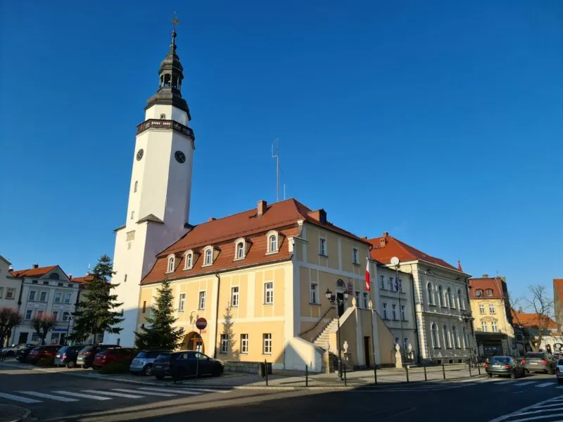 Budynek ratuszowy w Mirsku z żółtą elewacją i białą wieżą przy ładnej pogodzie