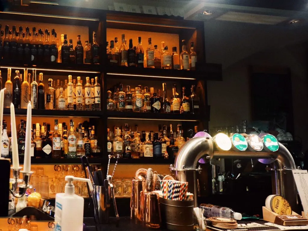 Bar w restauracji, widoczny regał, na którym są wystawione napoje alkoholowe.