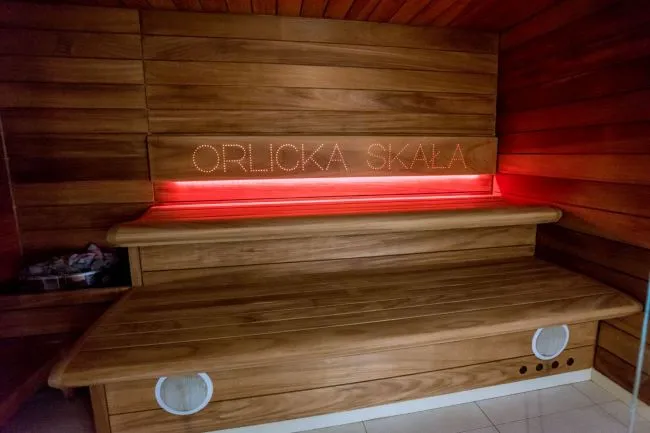 Drewniana sauna z neonowym napisem Orlicka Skała i czerwonym światłem. 