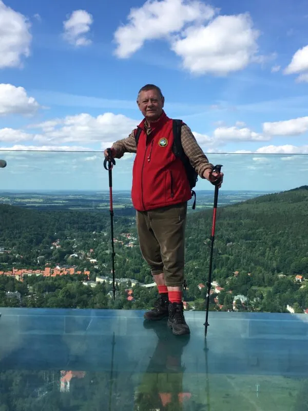 meżczyzna w czerownym polarze stojący na przeszklonej podłodze wysoko na ziemia