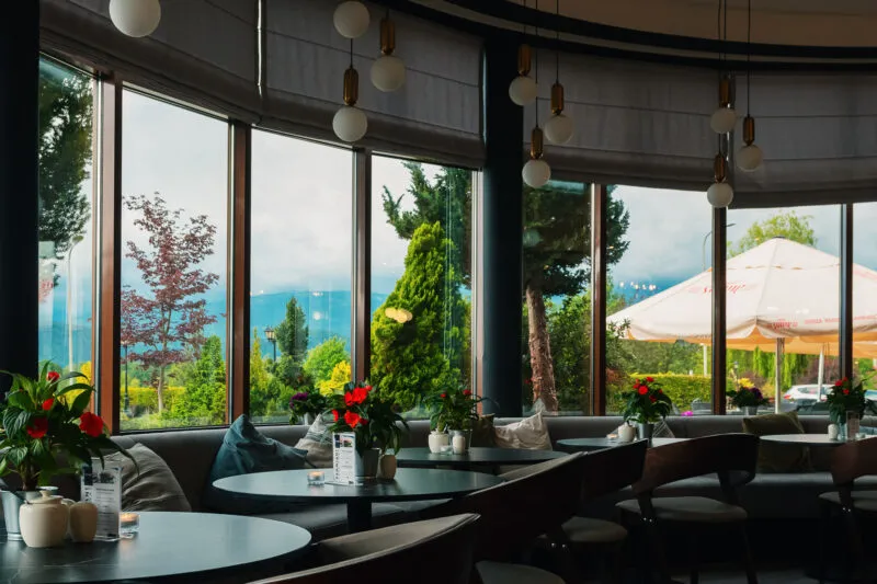 Le restaurant vitré de l'hôtel Kyriad Karkonosze dispose de tables sombres, de fauteuils moelleux et de lampes suspendues, et un jardin verdoyant avec une terrasse s'étend derrière les fenêtres.