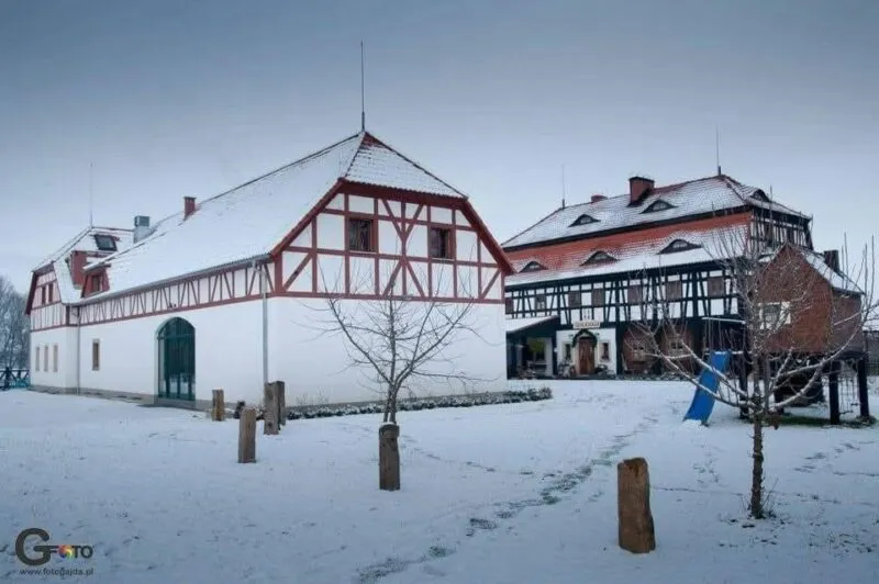 Trójkondygnacyjny budynek szachulcowy w zimowej scenerii. 