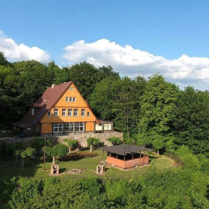 Pomarańczowy Dom Turysty z lotu ptaka, otoczony zielenią.