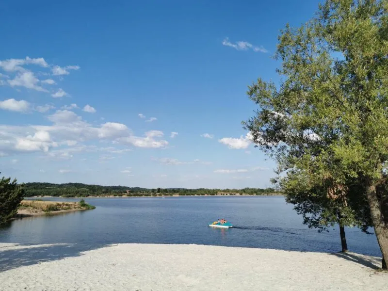 Zdjęcie przedstawiające piaszczystą plażę i turystów wypoczywających na wodzie