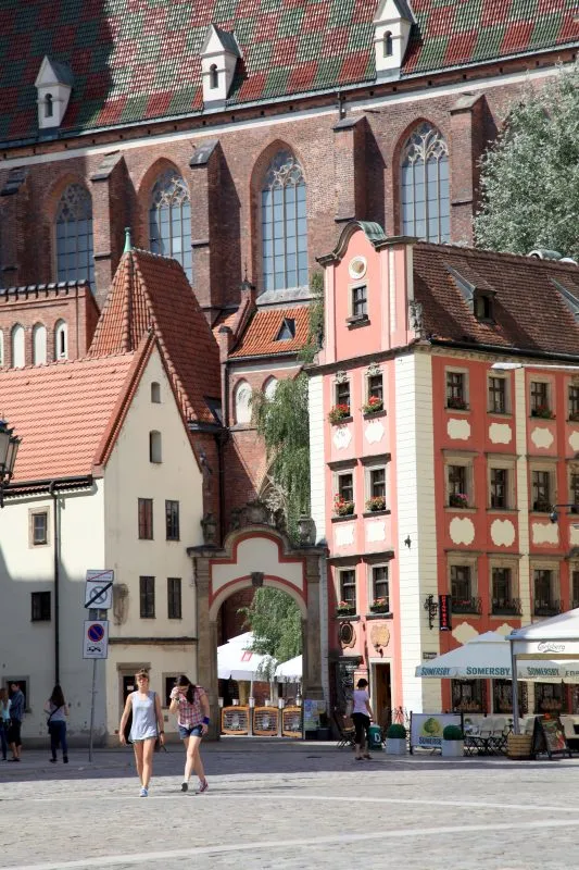 Niewielkie pastelowe budynki połączone bramą znajdujące się na wrocławskim rynku.