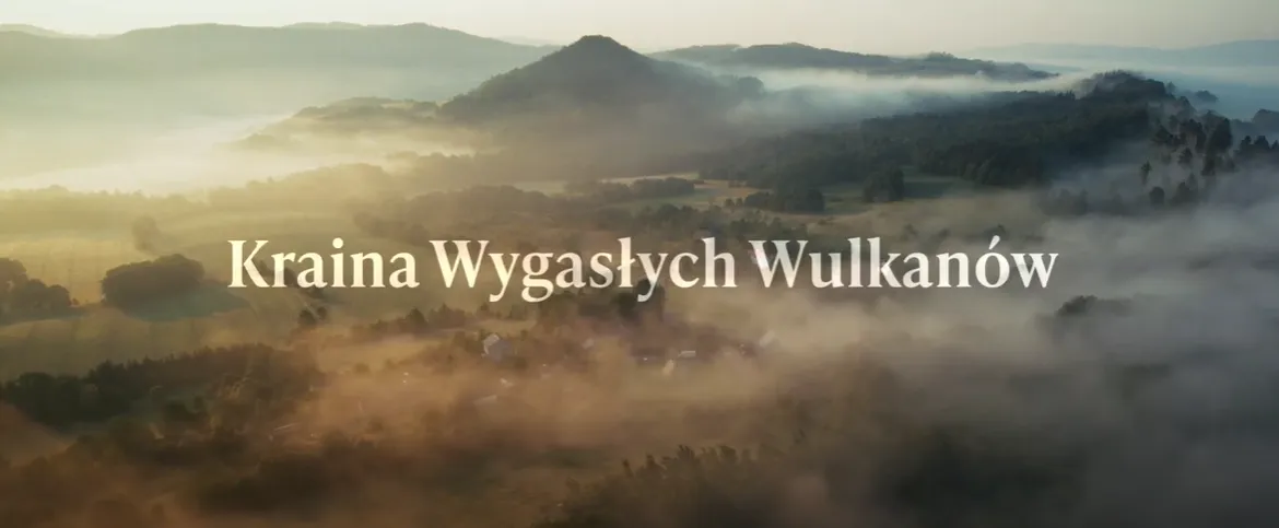 piękne zdjęcie z drona ukazujące krainę wygasłych wulkanów, w tym mgłę zza której wystaje wzgórze