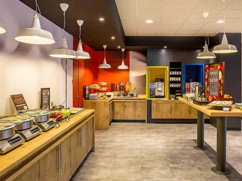 Pomieszczenie restauracyjne. Wokół ścian ustawione komody, na których znajdują się przyszykowane dania śniadaniowe.