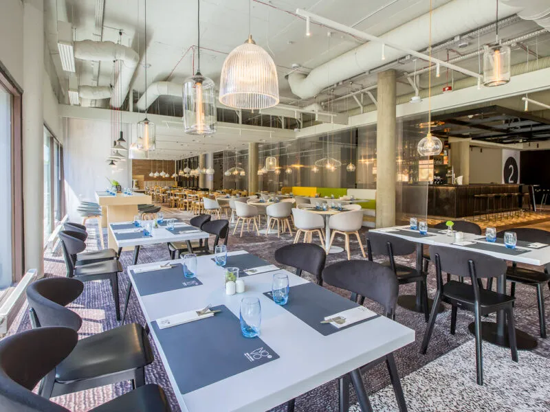Ekskluzywna nowoczesna restauracja ze kilkunastoma stolikami i krzesłami.