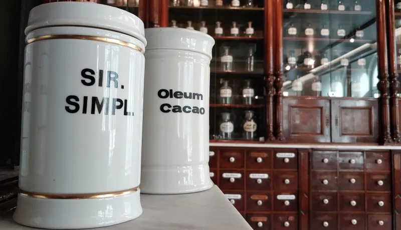 Biały dawny ceramiczny pojemnik farmaceutyczny w tle wyposażenie dawnej apteki