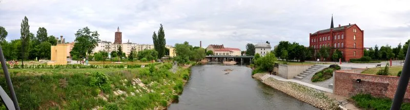 panorama rzeki, po bokach rzeki znajduję się zabudowanie, po lewej stronie budynki są żółte a po prawej czerwone