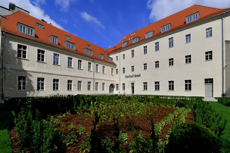 Odnowiony budynek klasztorny. Na pierwszym planie dziedziniec wewnętrzny z małą architekturą zieloną.