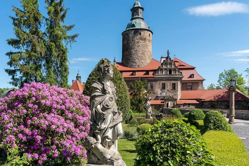 Widok na zamek znajdujący się w oddali natomiast na pierwszym planie widać mnóstwo kolorowych roślin w ogrodzie
