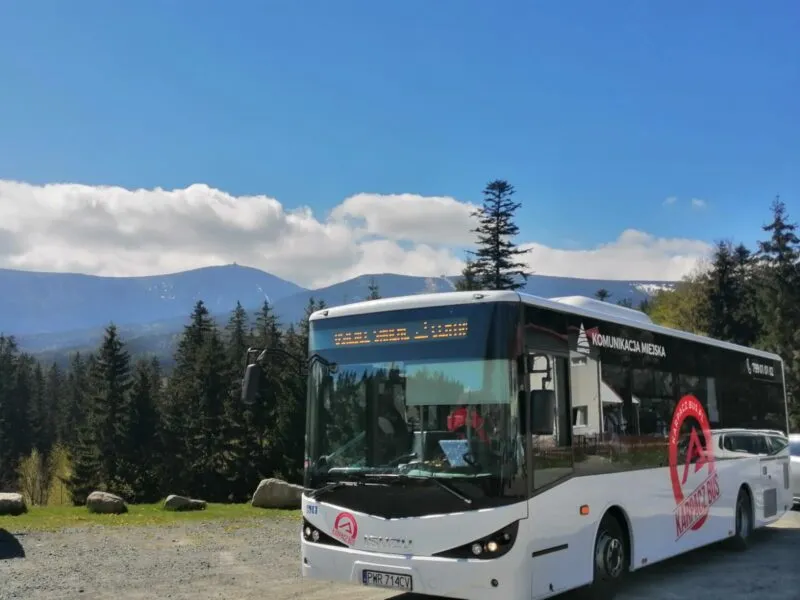 Biały autobus firmy Vip Travel na tle Karkonoszy