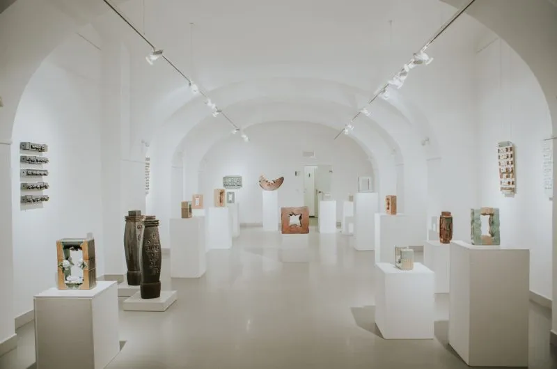 Wnętrze galerii sztuki- białe ściany z białymi cokolikami i stojącymi na nich rzeźbami
