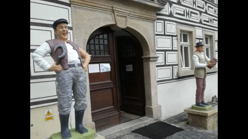 wejście do muzeum, po bokach drzwi stoją dwie wysokie figurki przedstawiające mężczyzn