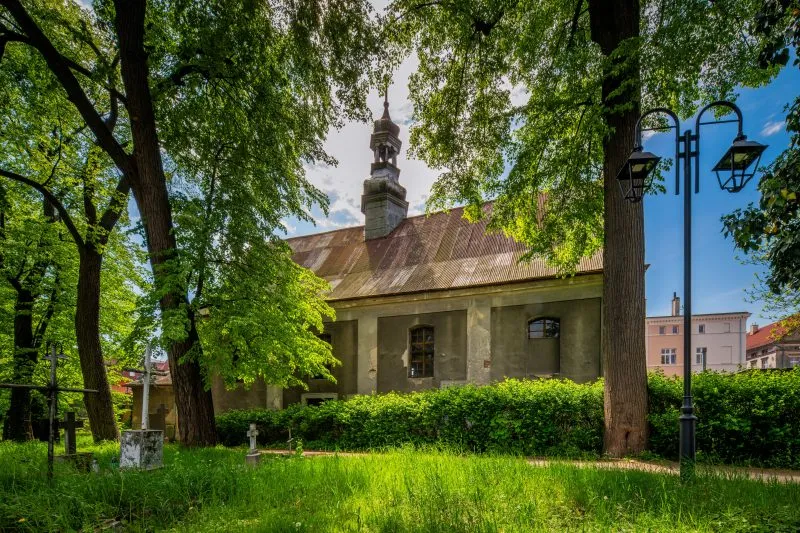 Na zdjęciu widać potężny, ceglany kościół św. Mikołaja z wysoką wieżą i ostrołukowymi oknami, stojący przy ząbkowickim rynku.