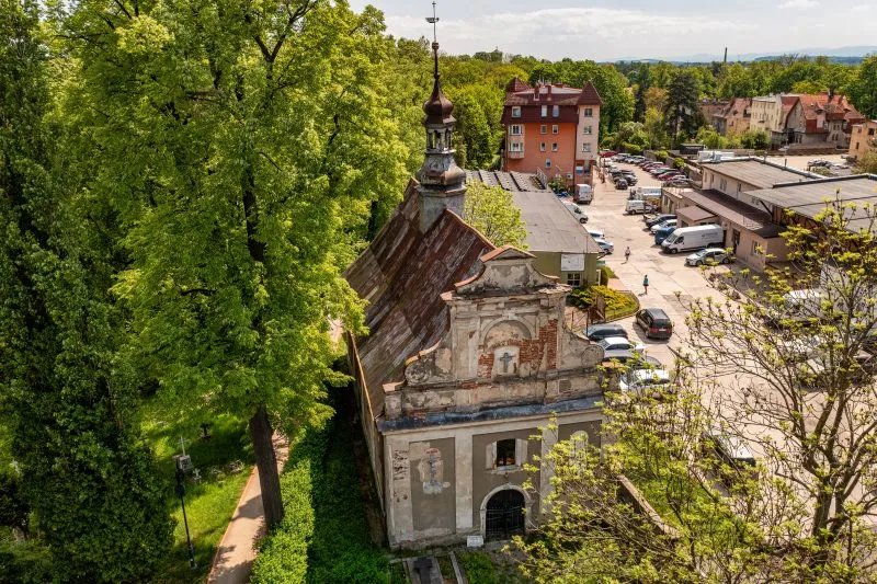 Na zdjęciu z lotu ptaka widać okazały, gotycki kościół z wysoką wieżą i ceglanymi murami, górujący nad zabytkowym centrum Ząbkowic Śląskich.
