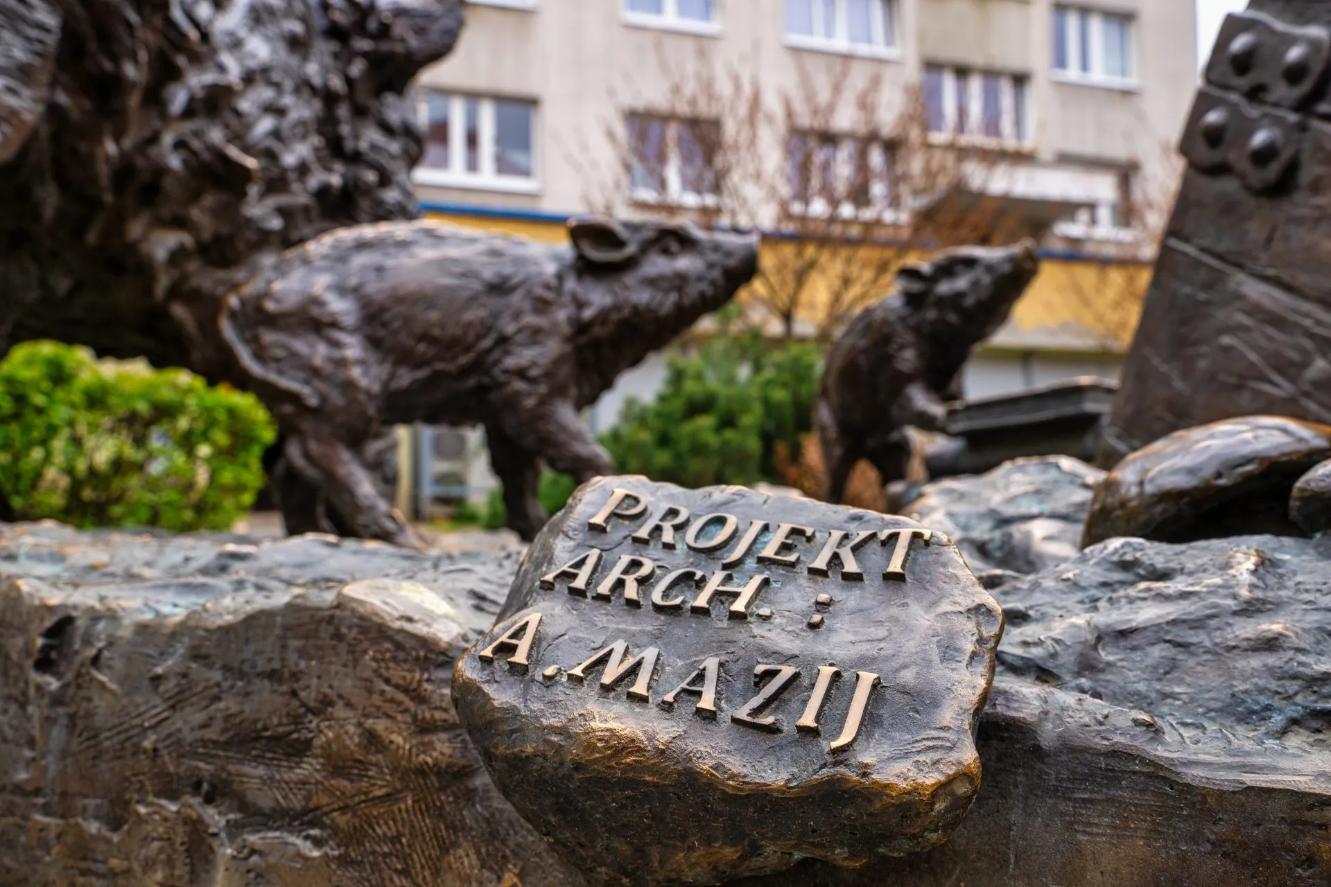 Na zdjęciu widać grupę realistycznych rzeźb dzików w różnych pozach, wykonanych z brązu, oddających ich dziką naturę i dynamikę ruchu.