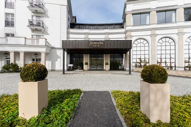 Wejście do eleganckiego hotelu z dwoma kwietnikami na pierwszym planie