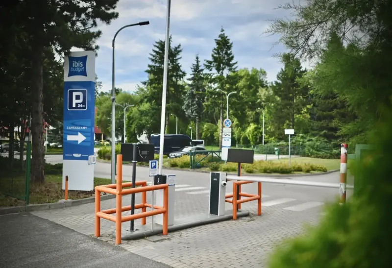 L'ingresso al parcheggio dell'hotel ibis Budget Wrocław Stadion è segnalato da cartelli blu, una freccia, una sbarra e barriere arancioni.