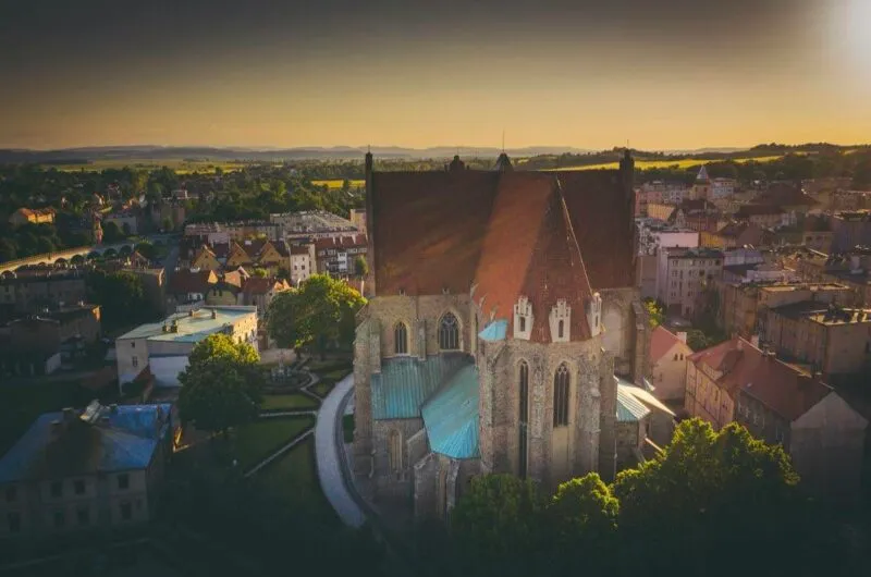 Grafika ilustracyjna do wydarzenia Strzegom a capella ze strzegomską bazyliką uchwyconą z drona