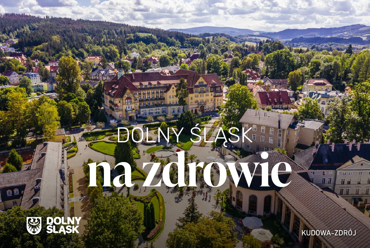 Okładka kampanii „Dolny Śląsk na zdrowie” pokazuje z lotu ptaka uzdrowiskową zabudowę Kudowy-Zdroju, otoczoną parkami i górskimi wzgórzami.