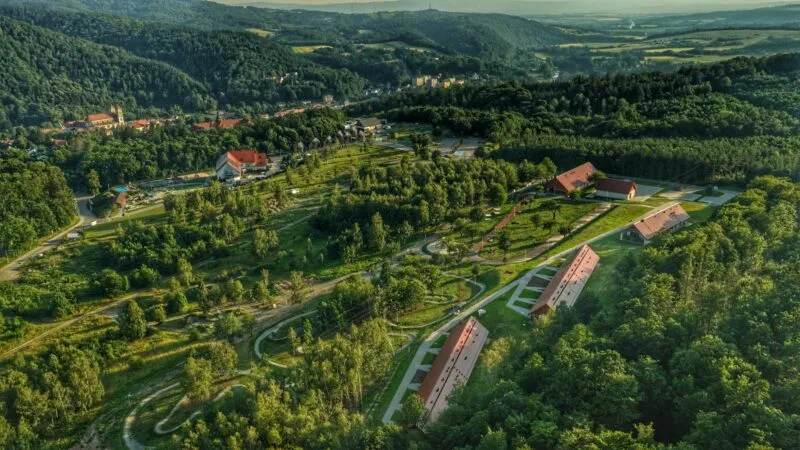 Pohled z dronu na ubytovací centrum na pozadí zeleně a kopců.